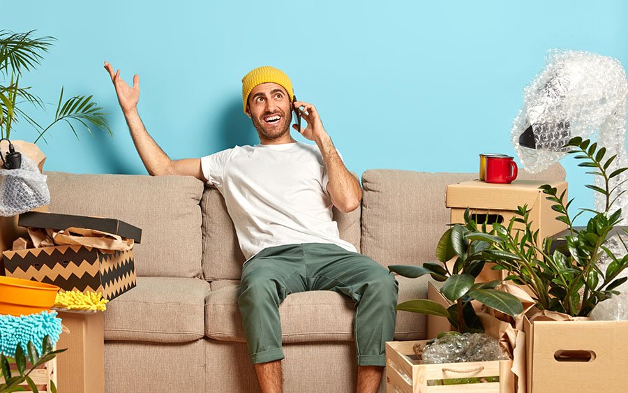 Ein Mann der auf der Couch sitzt und motiviert ein Telefonat führt