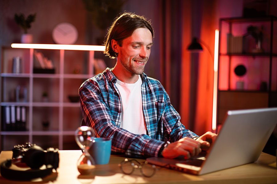 Ein glücklicher Mann der mit seinem Laptop im Internet surft